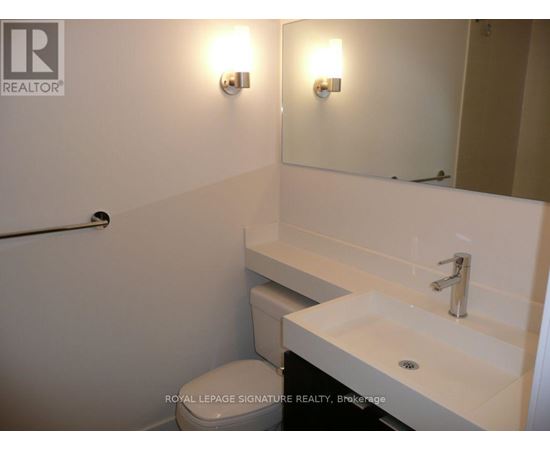 A white bathroom with a toilet, sink, and mirror.