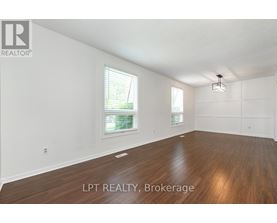 A spacious room with wooden flooring and white walls.