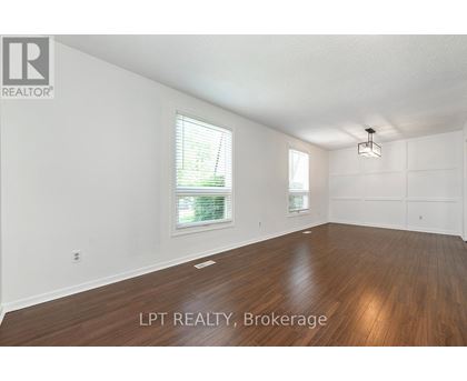 A spacious room with wooden flooring and white walls.