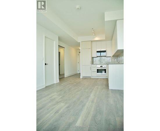 A spacious kitchen with white cabinets and a wooden floor.