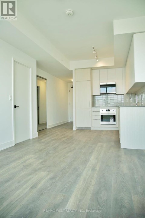 A spacious kitchen with white cabinets and a wooden floor.