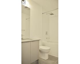 A white toilet in a bathroom with a white tub and a white sink.