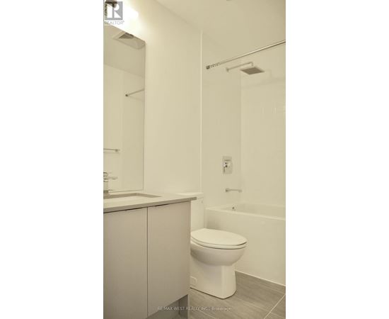 A white toilet in a bathroom with a white tub and a white sink.