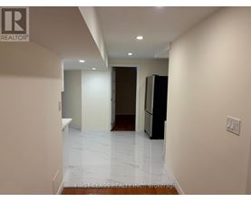 A hallway with a refrigerator on the right and a door at the end.