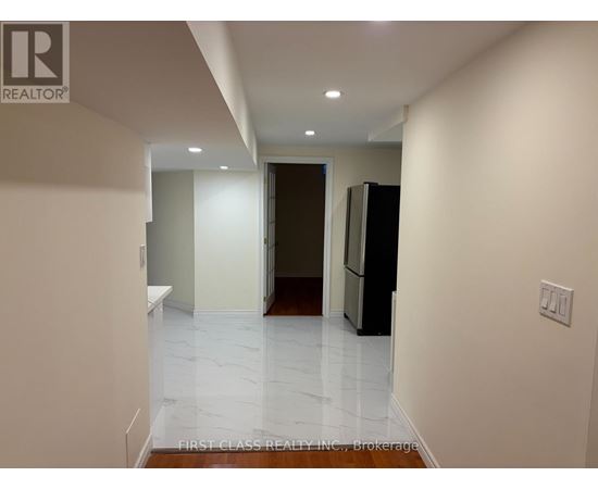 A hallway with a refrigerator on the right and a door at the end.