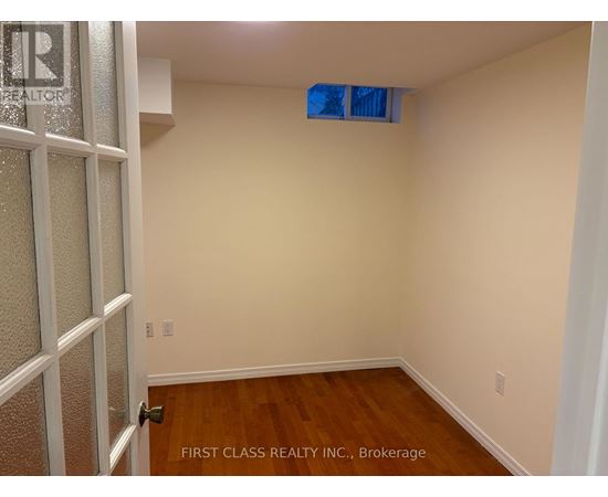 A room with wooden flooring and a door on the left.