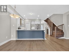 A spacious living room with a staircase leading to the upper floor.