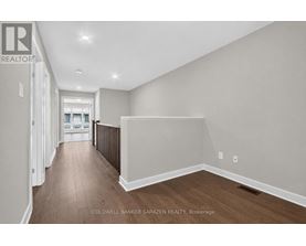 A spacious room with wooden flooring and white walls, with a doorway leading to another room visible in the distance.