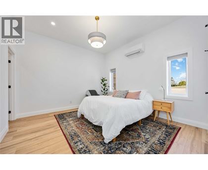 A bedroom with a white bed and a rug on the floor.