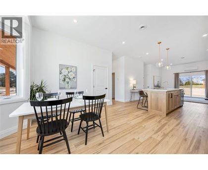 A dining room with a table set for two and a kitchen area in the background.