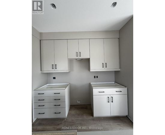 A white kitchen with a refrigerator, sink, and cabinets.