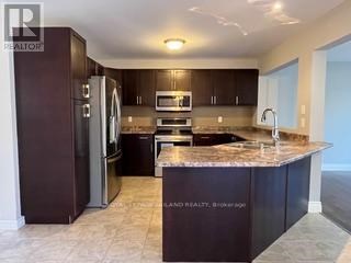 A kitchen with dark brown cabinets and granite countertops.