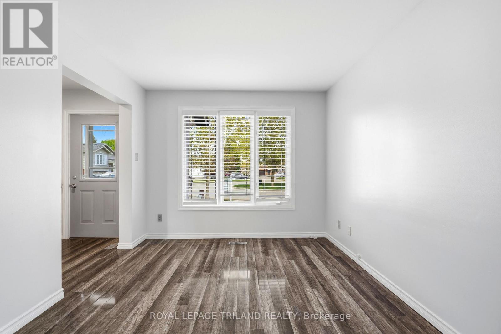 A room with a wooden floor and a window with blinds.