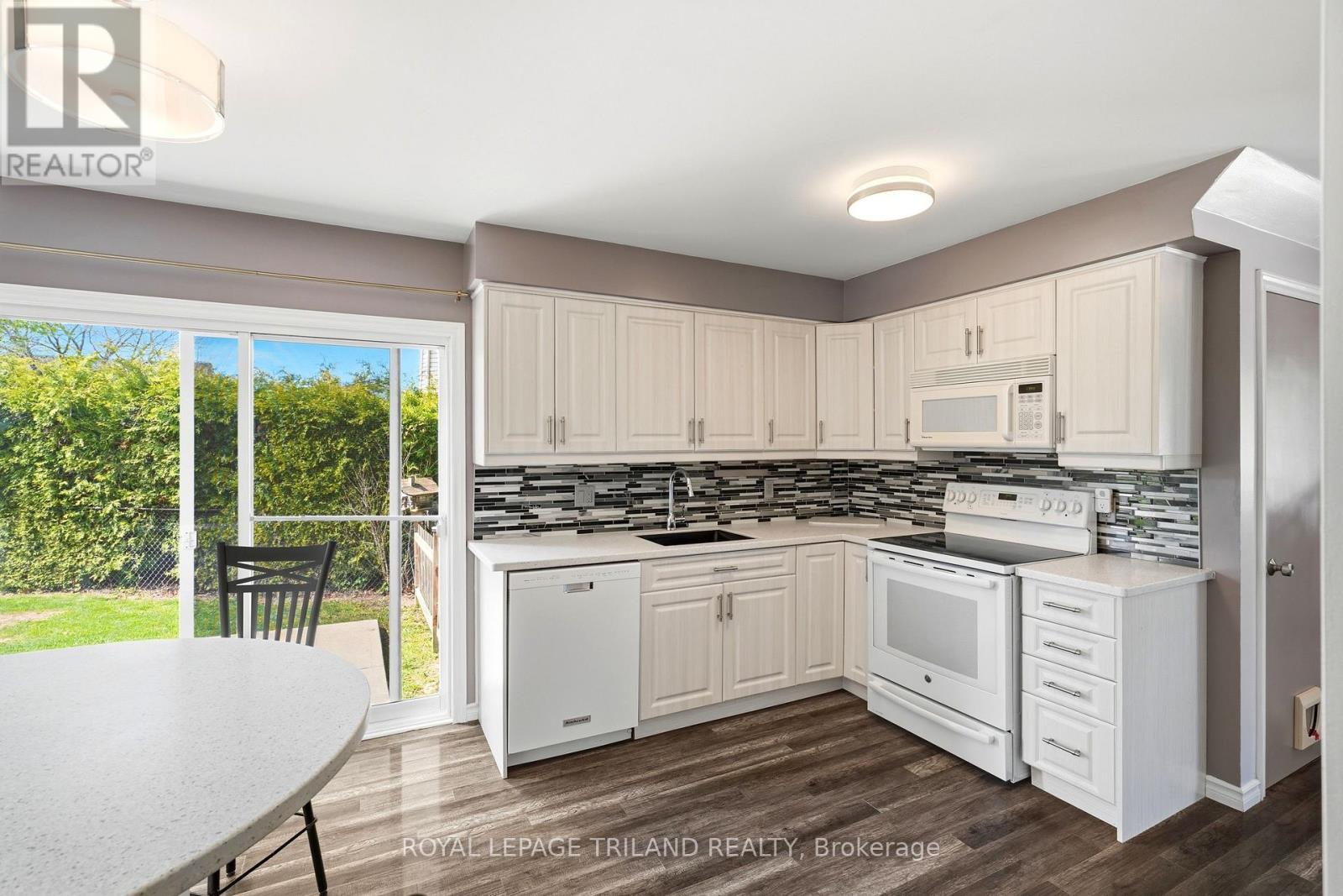 A kitchen with white cabinets and a black chair.