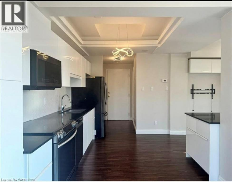 A modern kitchen with black countertops and white cabinets.