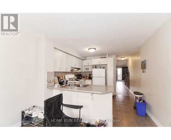 A kitchen with a black chair and a blue bin on the floor.