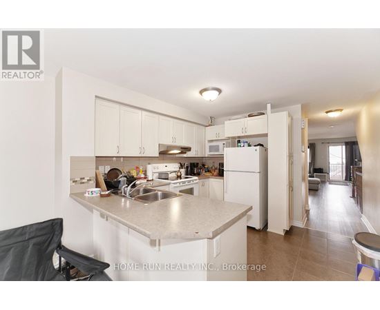 A kitchen with a sink, refrigerator, and cabinets.