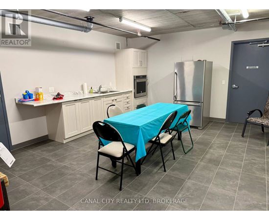A kitchen area with a table covered in a blue tablecloth and chairs around it.