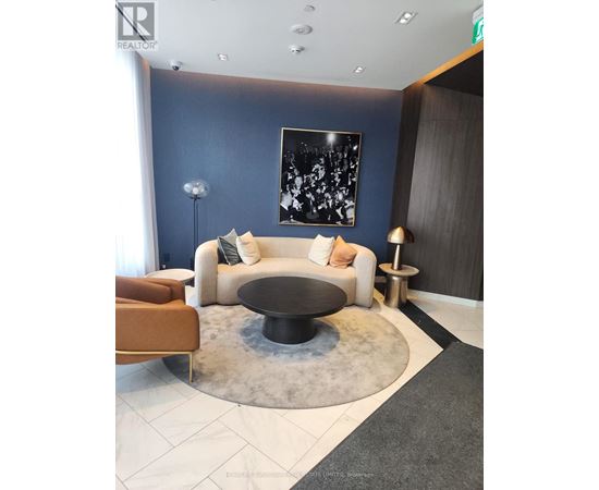 A modern living room with a white couch, a black coffee table, and a large abstract painting on the wall.