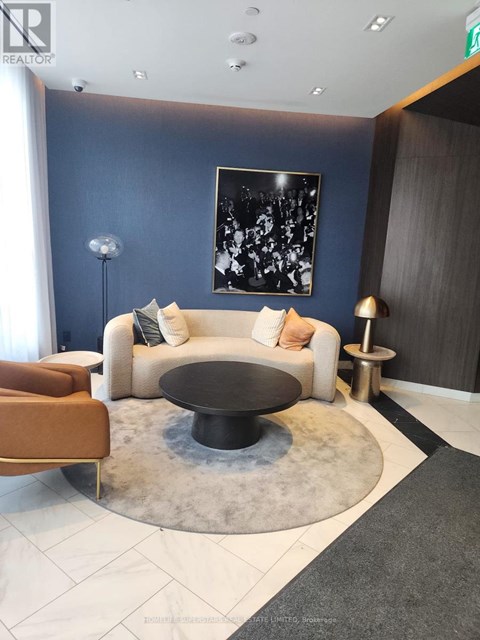 A modern living room with a white couch, a black coffee table, and a large abstract painting on the wall.