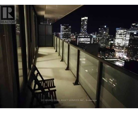 A balcony with a chair and a view of the city at night.