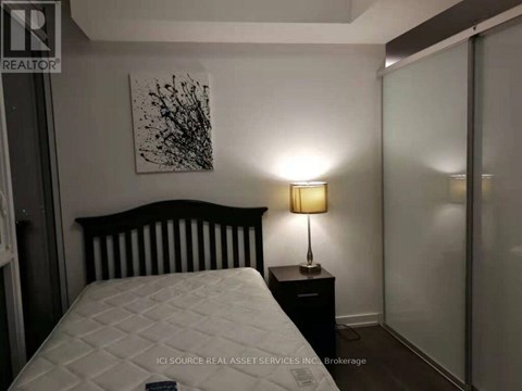 A bedroom with a white bed and a black and white painting on the wall.