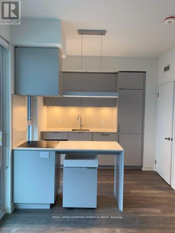A modern kitchen with a sink, dishwasher, and refrigerator.