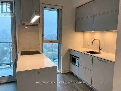A modern kitchen with white cabinets and a large window.