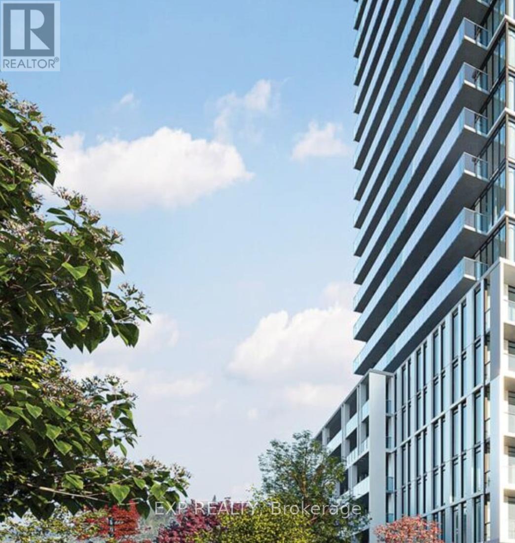 A tall building with many windows is surrounded by trees and bushes.