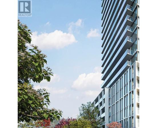 A tall building with many windows is surrounded by trees and bushes.