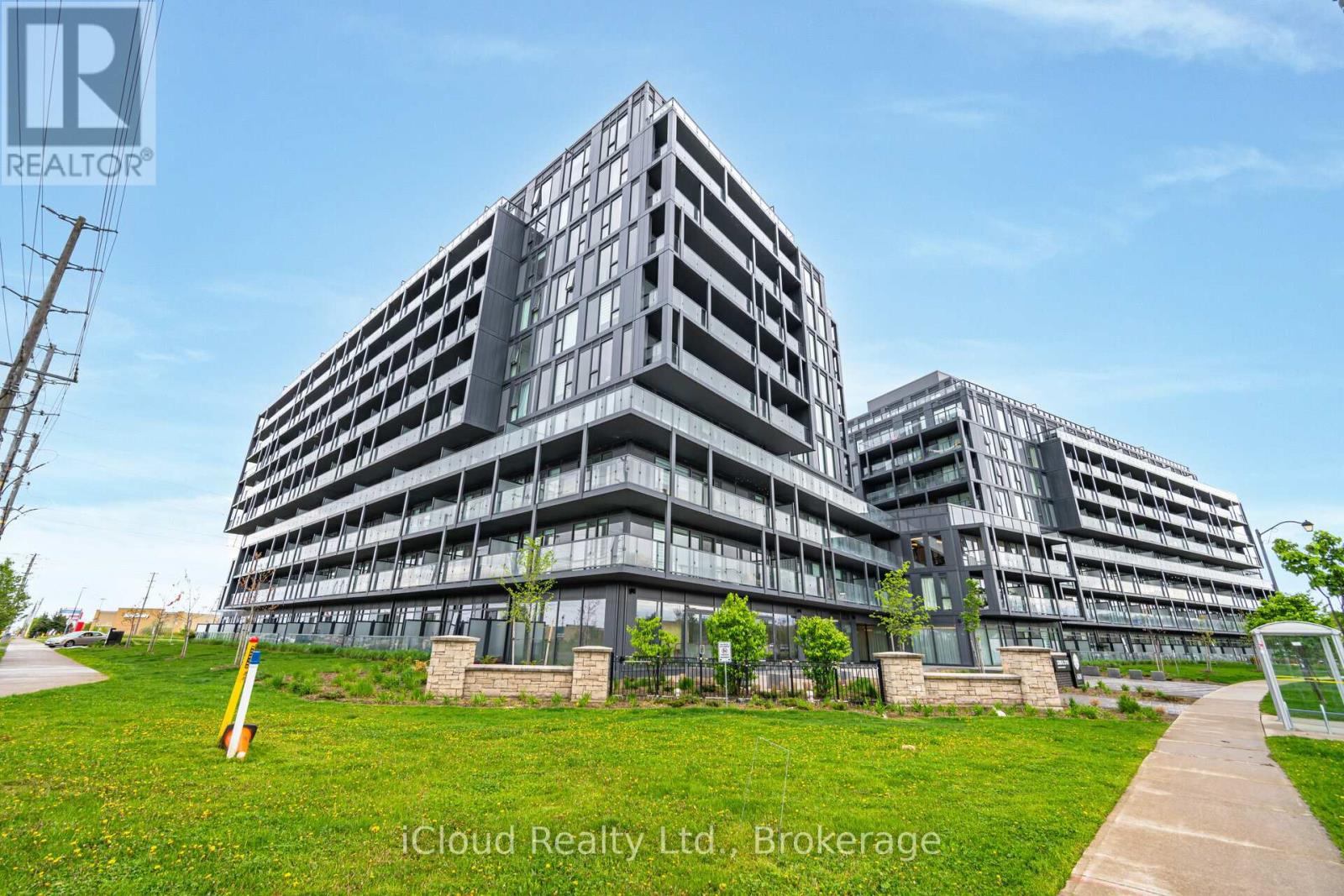 A modern multi-story building with a grassy area in front and a clear blue sky above.