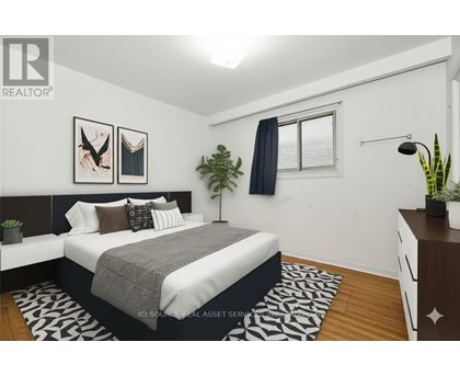 A bedroom with a bed, nightstand, and a plant.