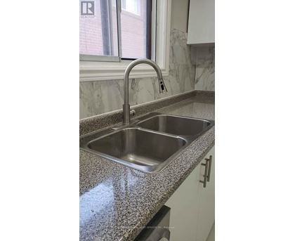 A kitchen sink with a granite countertop and a chrome faucet.
