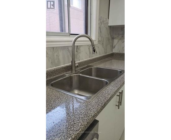 A kitchen sink with a granite countertop and a chrome faucet.