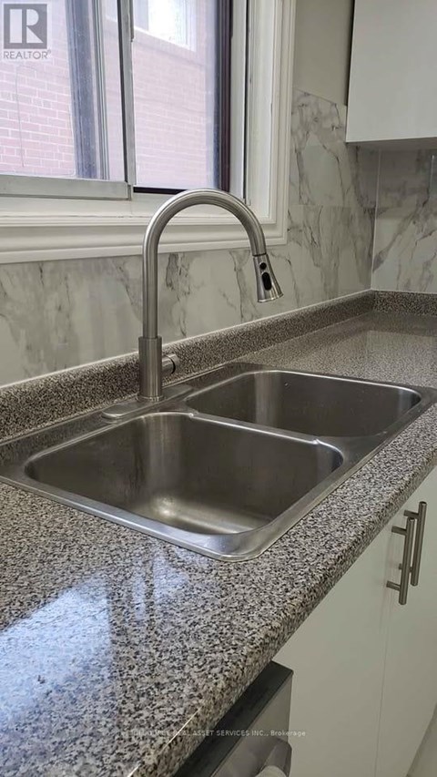 A kitchen sink with a granite countertop and a chrome faucet.