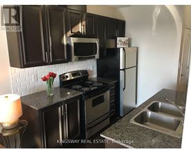 A kitchen with black cabinets and a white fridge.