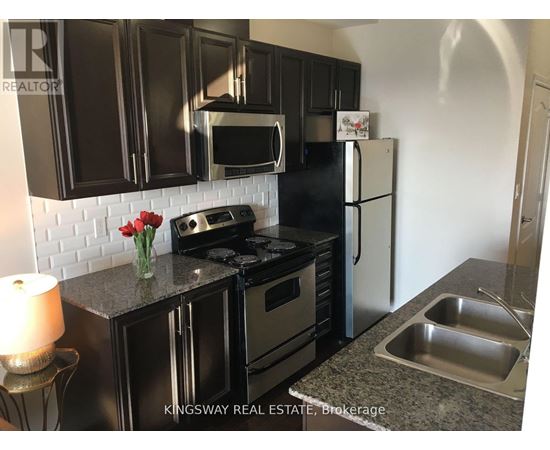 A kitchen with black cabinets and a white fridge.