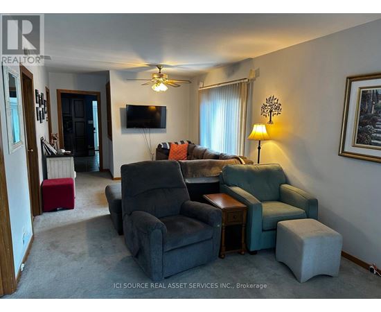 A living room with a grey couch, a black chair and a red ottoman.