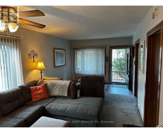 A living room with a grey couch and a ceiling fan.
