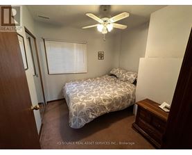 A bedroom with a bed, dresser, and ceiling fan.
