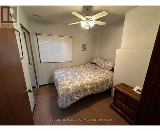 A bedroom with a bed, dresser, and ceiling fan.