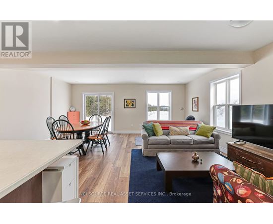 A living room with a couch, chairs, and a television.
