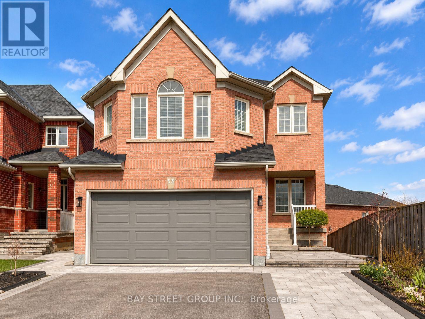 A large red brick house with a grey garage door in front.