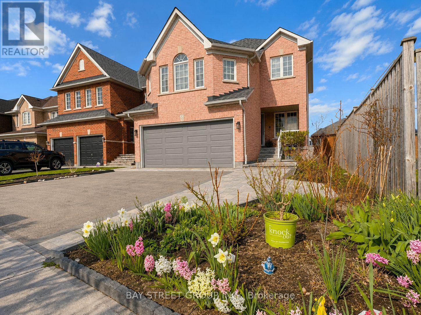 A large brick house with a garage and a well-maintained garden in front.
