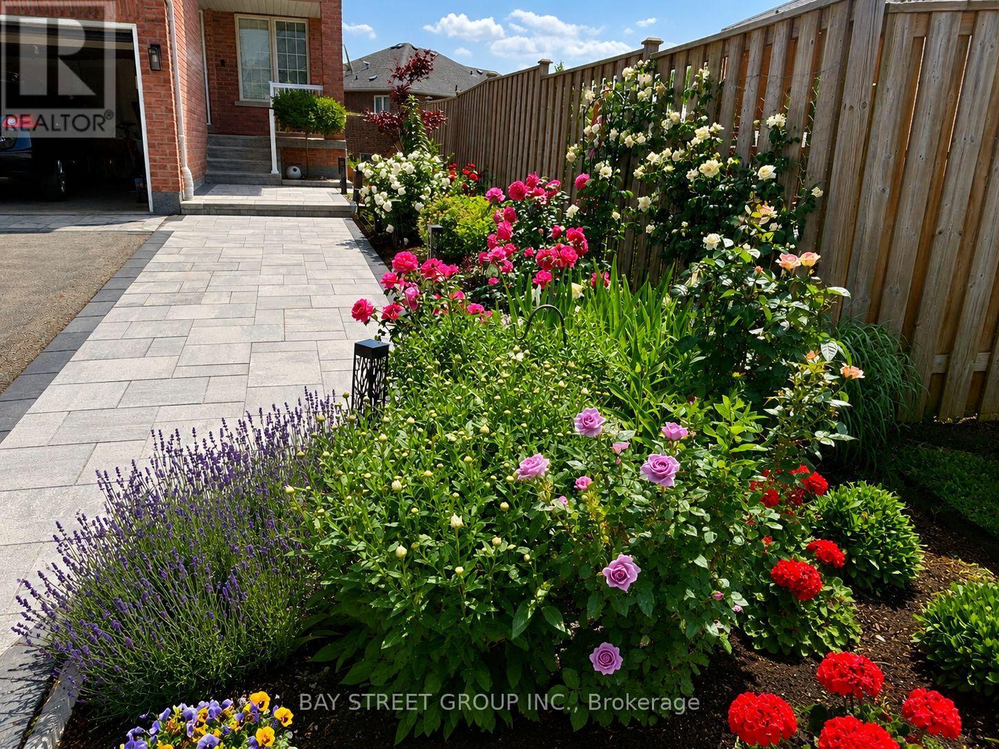 A flower bed with purple and red flowers in front of a brick house.