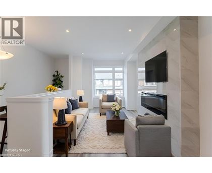A living room with a white sofa, a grey armchair, a coffee table, and a flat-screen TV mounted on the wall.