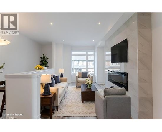 A living room with a white sofa, a grey armchair, a coffee table, and a flat-screen TV mounted on the wall.