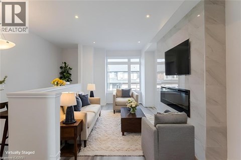 A living room with a white sofa, a grey armchair, a coffee table, and a flat-screen TV mounted on the wall.