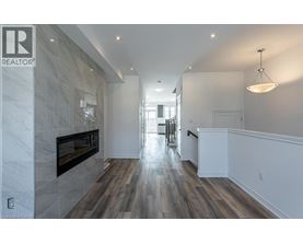 A spacious hallway with a fireplace and wood flooring.