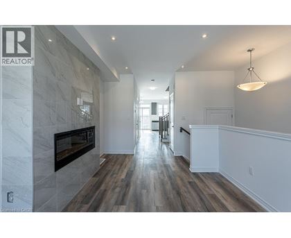 A spacious hallway with a fireplace and wood flooring.